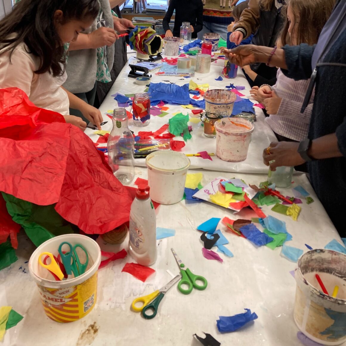 a photo of a table of crafting with families standing around and getting busy