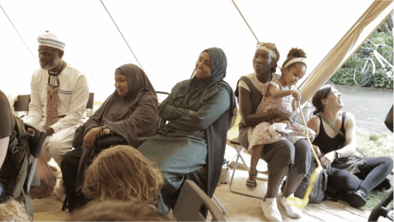 family audience sitting and listening to a storyteller in a marquee